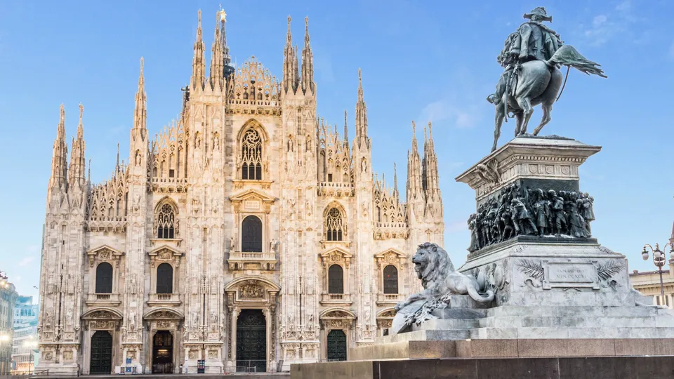 Facciata del Duomo di Milano con statua equestre in primo piano.