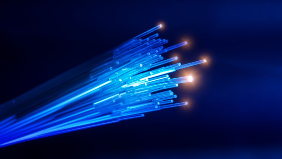 Nærbilde av en fiberkabel lyst opp i et blått lys.
