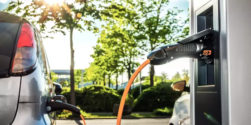 Elektrisk køretøj opladningskabel tilsluttet vægmonteret ladestation.