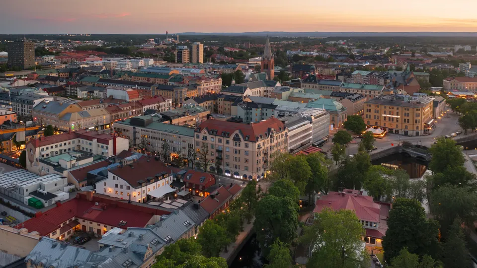 Flygfoto över Örebro i skymning med upplysta byggnader och en kyrktorn.