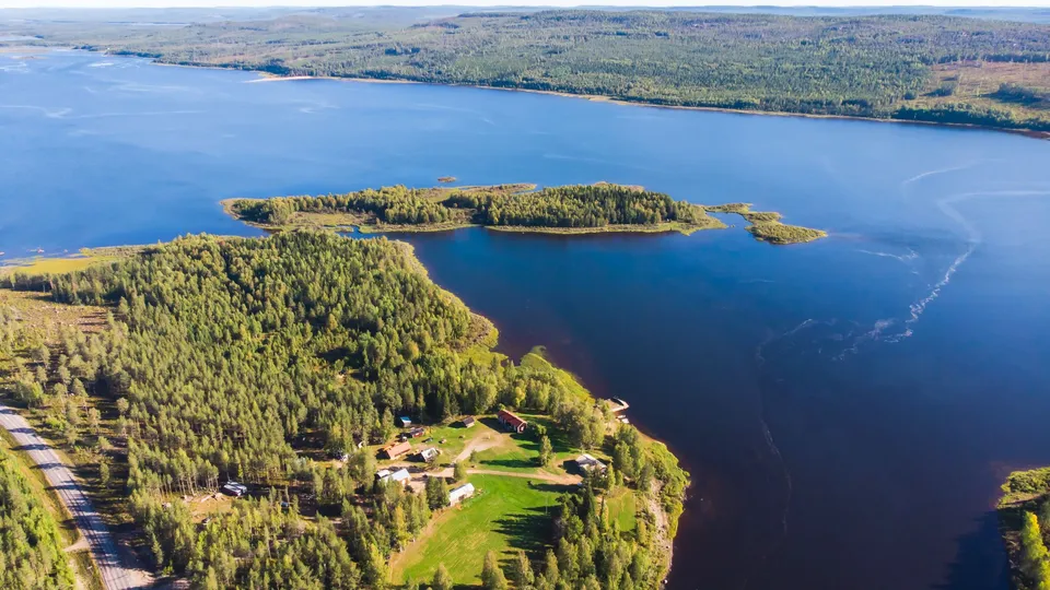 Utsikt över landskap med blått vatten och gröna skogar.