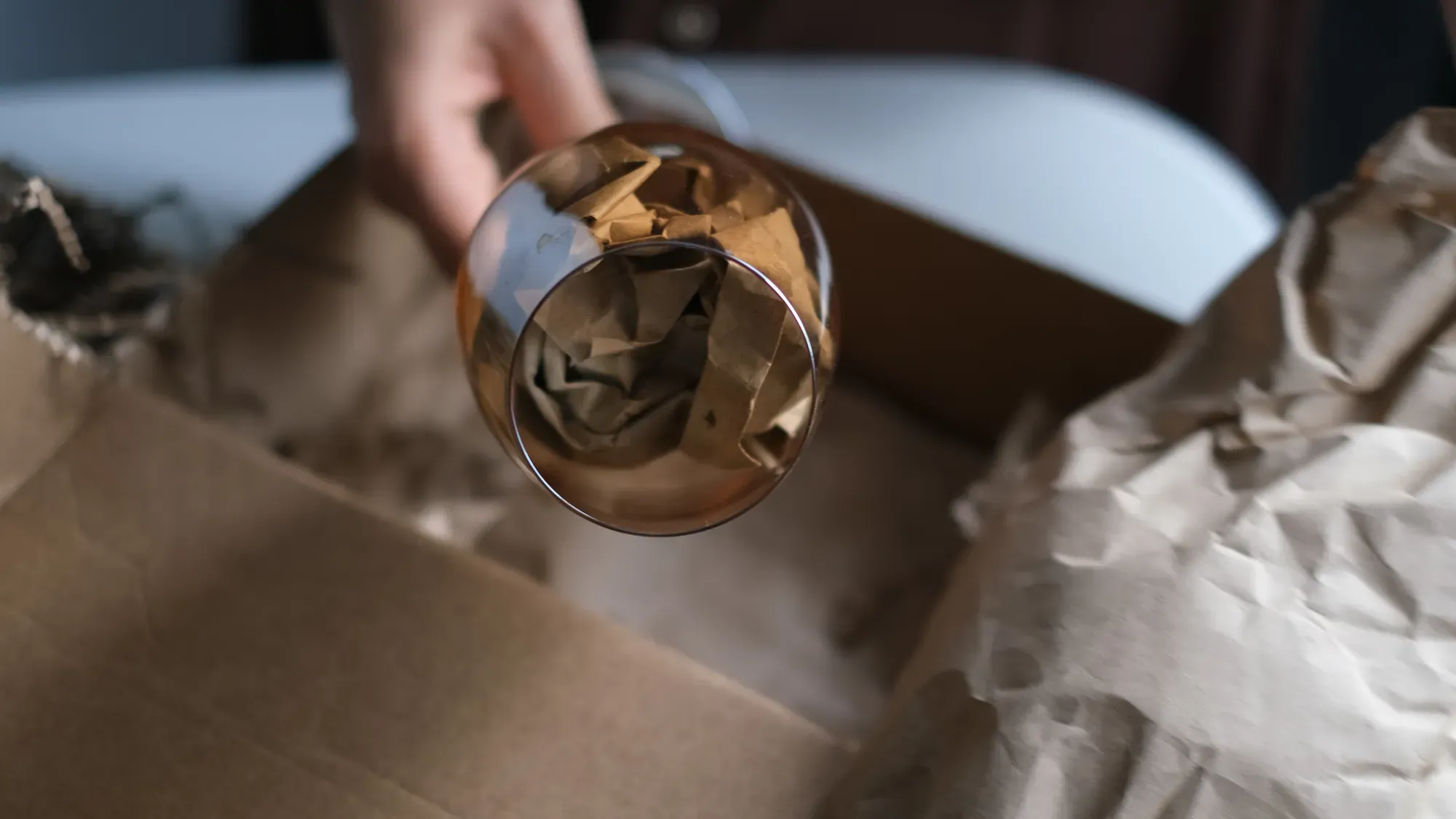 Vinglas med papper i kupan inför packning i flyttkartong.