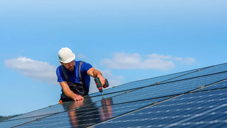 Trabalhador instalando painéis solares num telhado.