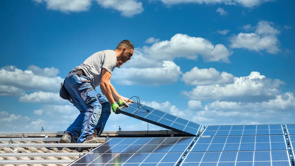 Trabajador instalando panel solar en azotea.