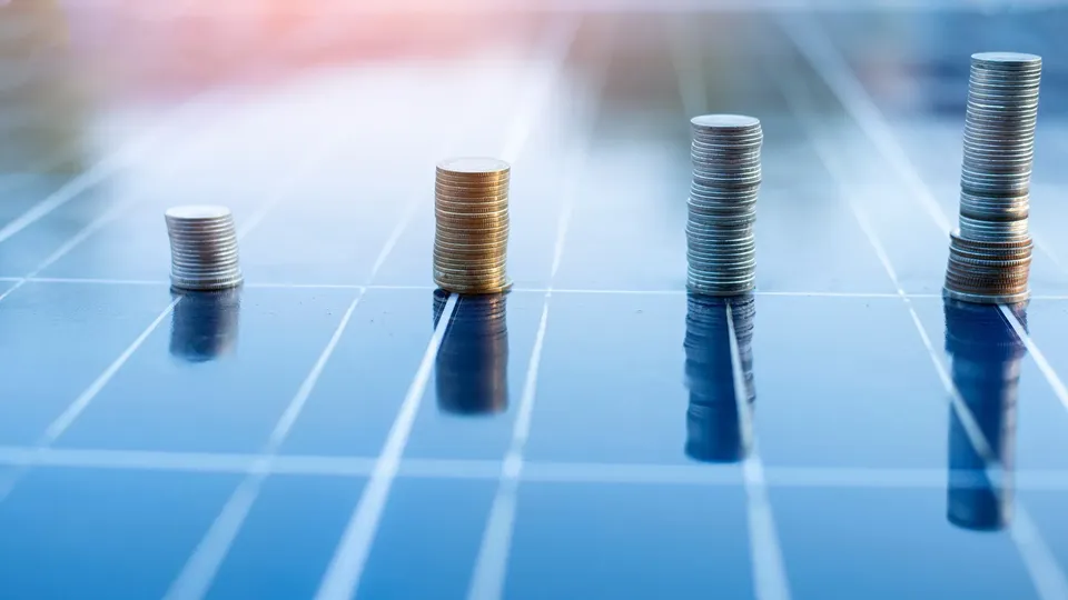 Stacks of coins on solar panels illustrating the financial benefits and funding opportunities for photovoltaic systems.