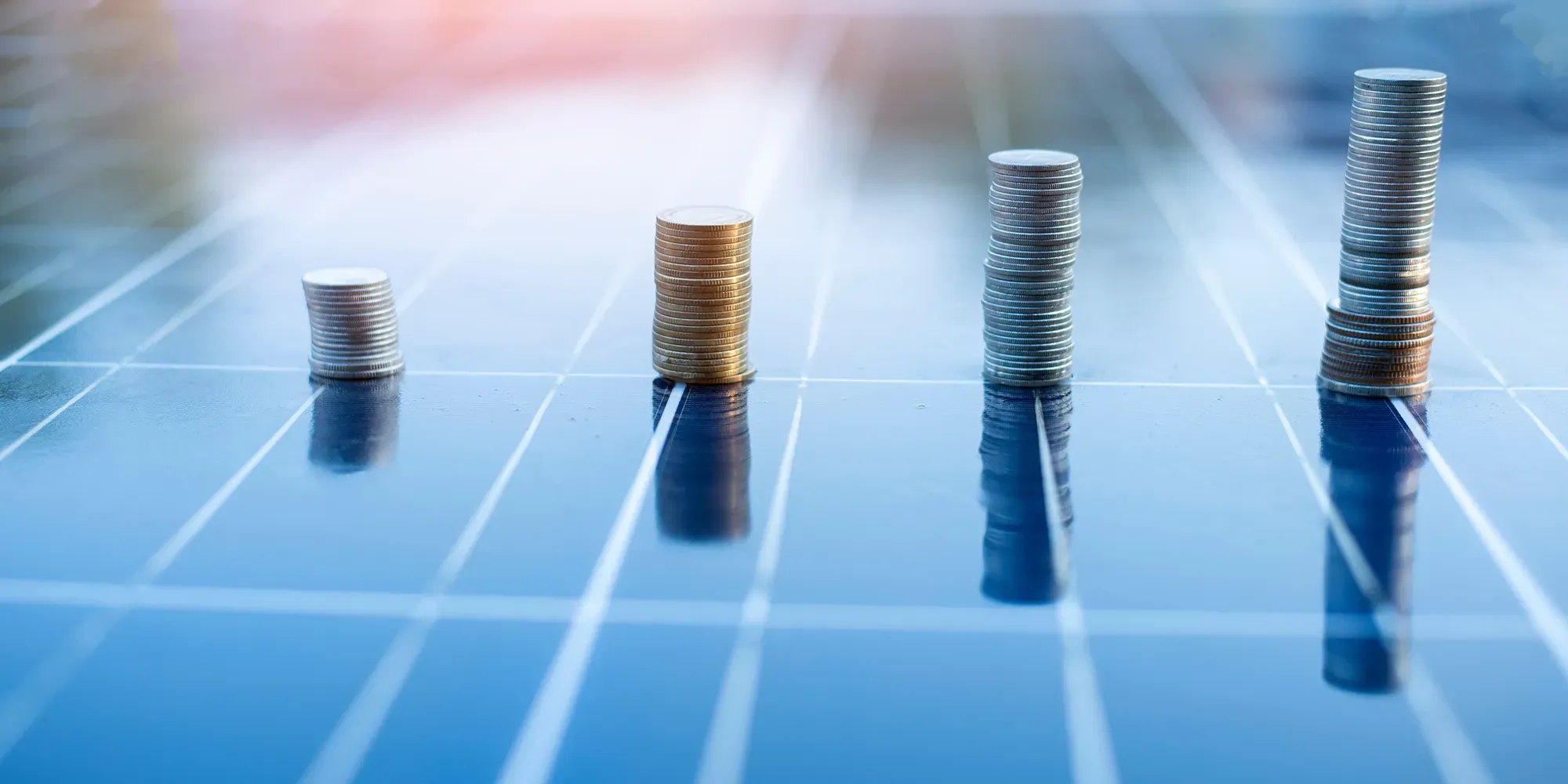 Münzstapel auf Solarmodulen veranschaulichen die finanziellen Vorteile und Fördermöglichkeiten einer Photovoltaikanlage.