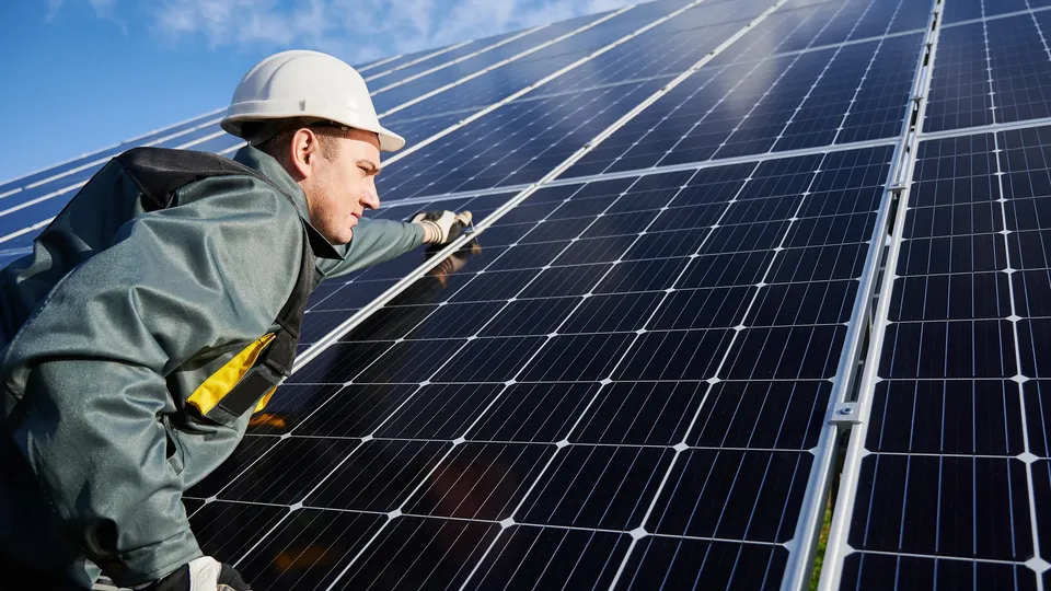 Techniker mit Schutzhelm montiert Solarmodule.