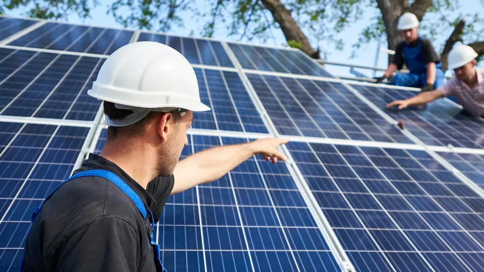 Techniker installieren eine Photovoltaikanlage mit Speicher auf dem Dach.