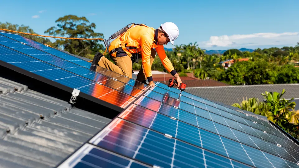 Trabalhador instalando painéis solares num telhado.