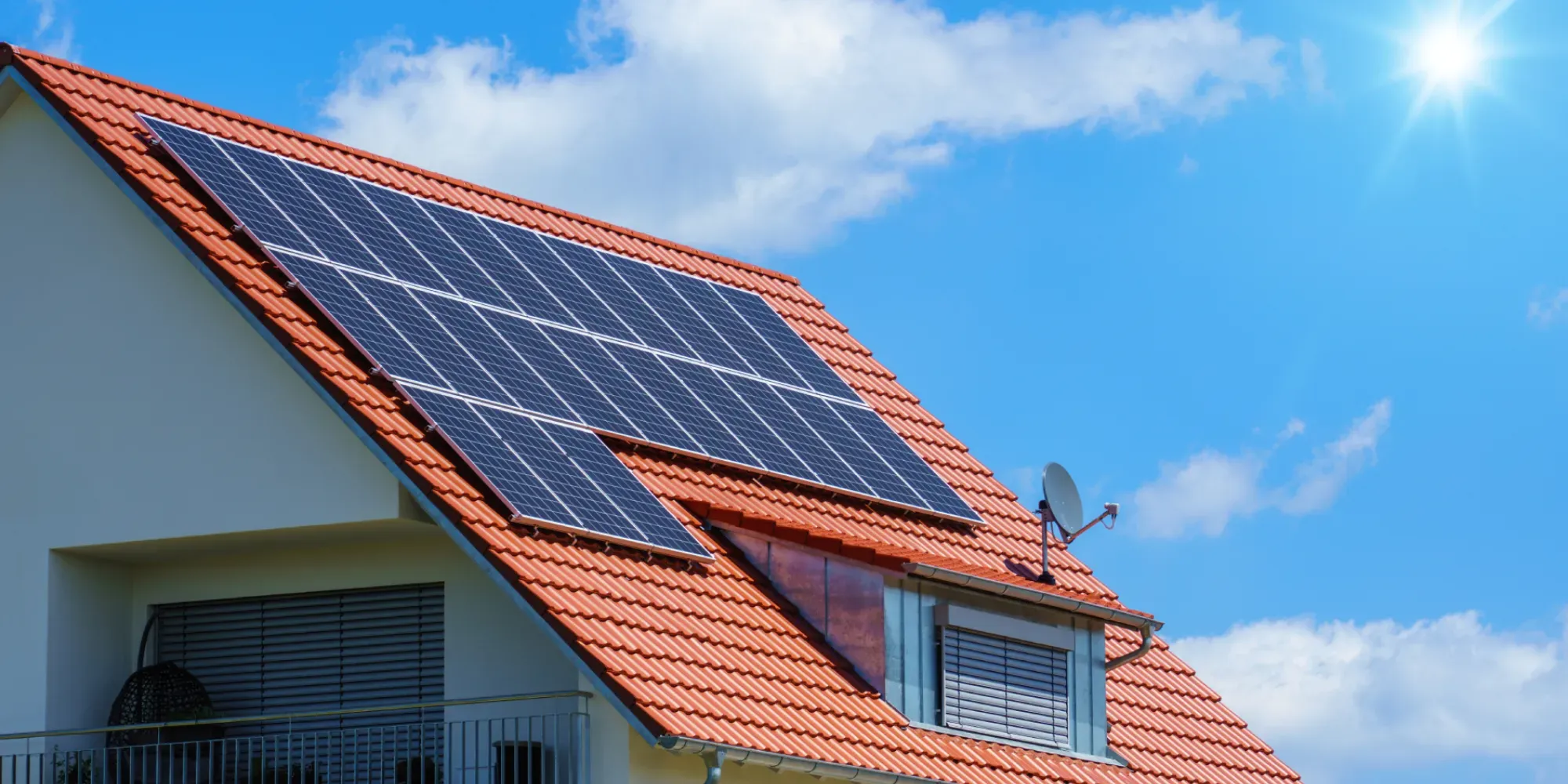 Paneles solares instalados en el techo de una casa con tejas rojas.
