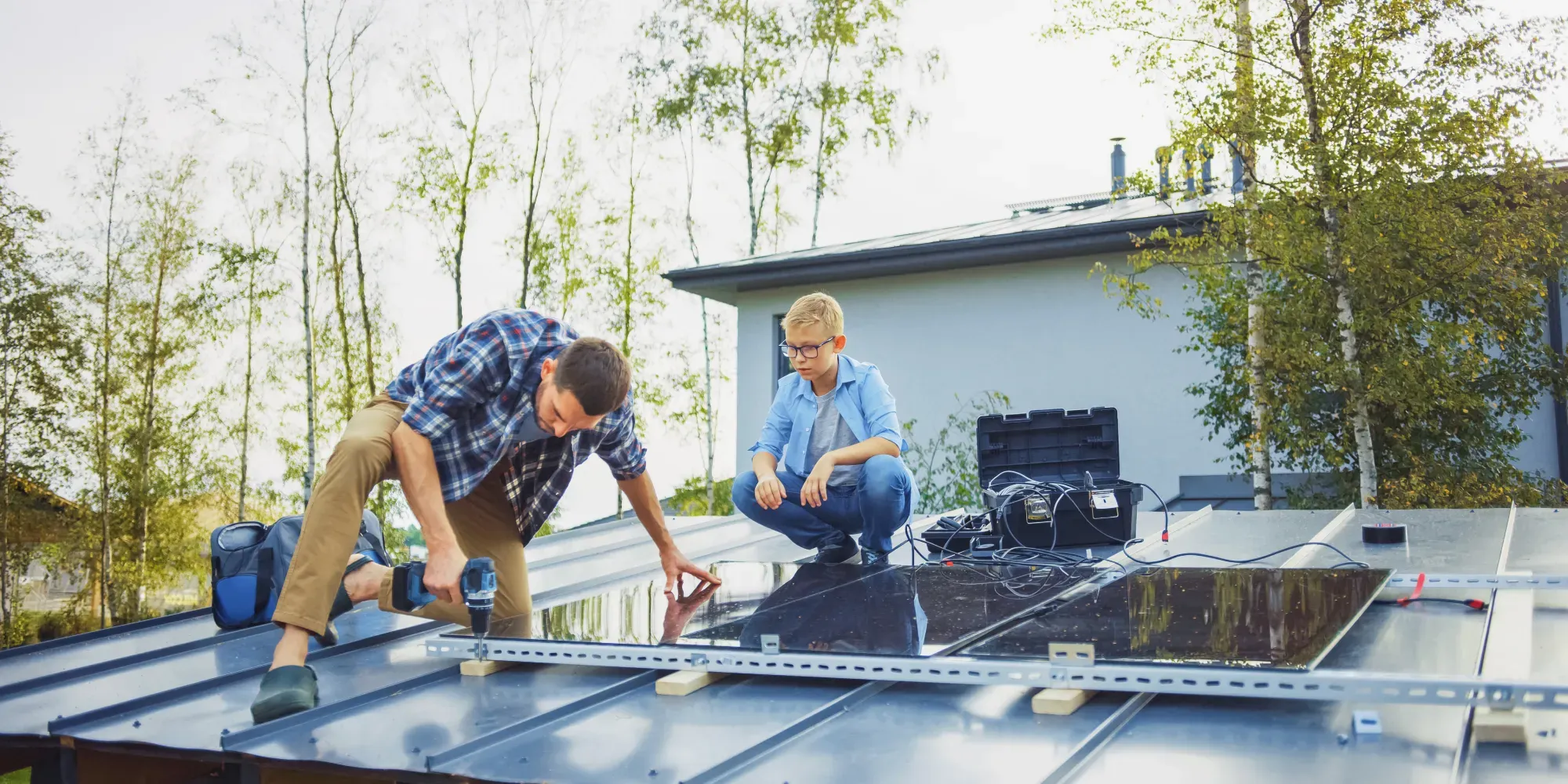Dos trabajadores instalando paneles solares en un techo.