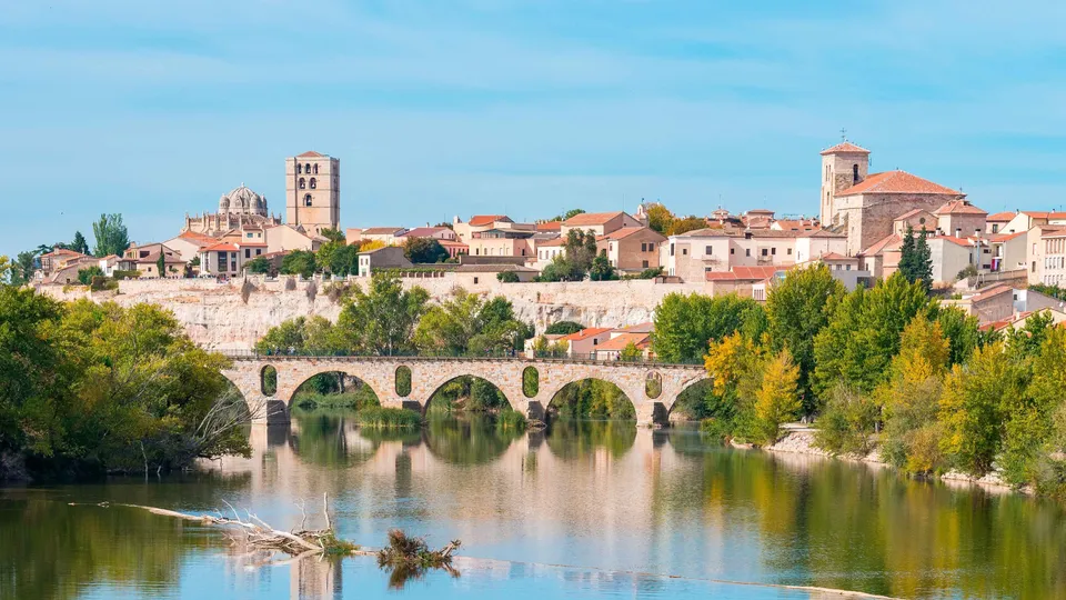 Pueblo medieval con puente de piedra sobre río.