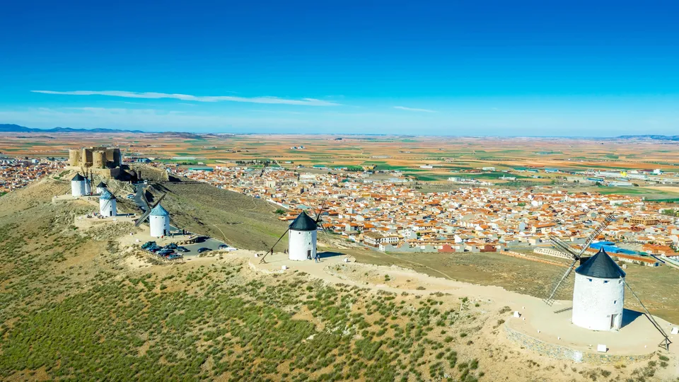 Molinos históricos en ladera con vista a pueblo y tierras de cultivo.