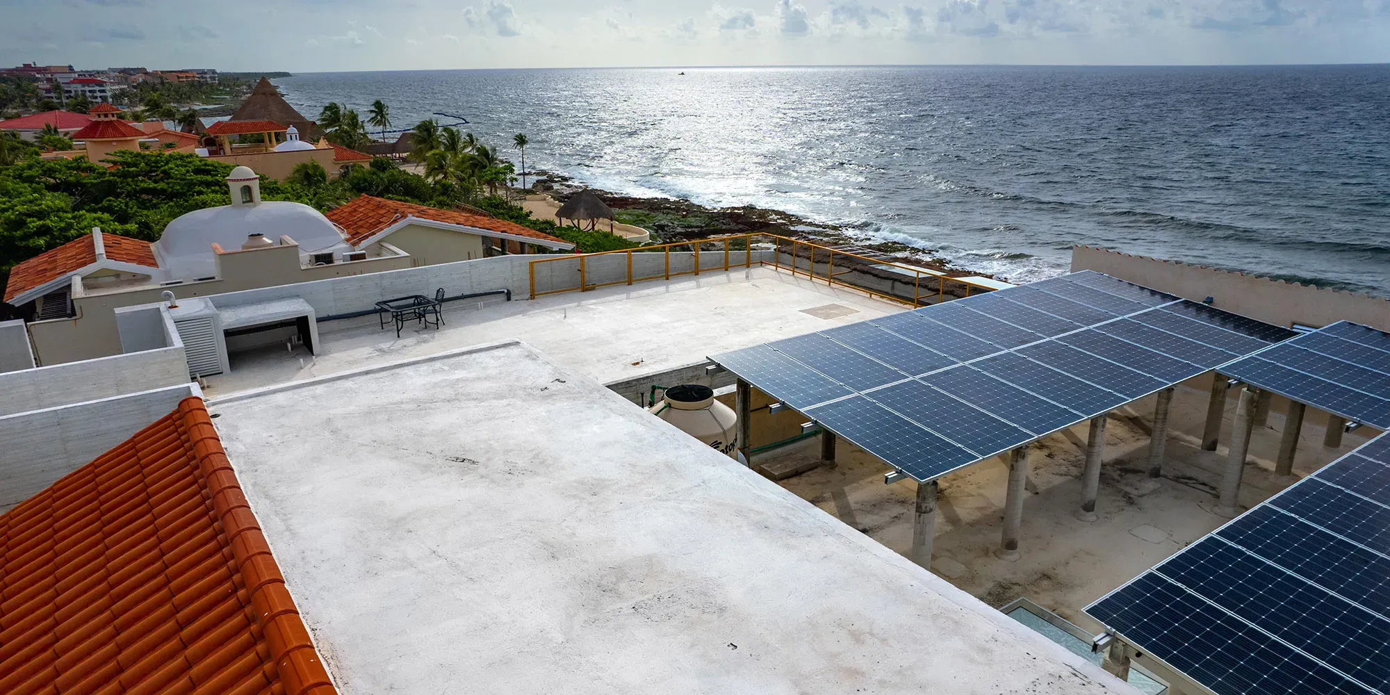 Azotea con paneles solares con vista al océano y edificios costeros.