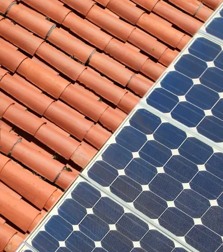 Tejas de barro junto a paneles solares oscuros en tejado.