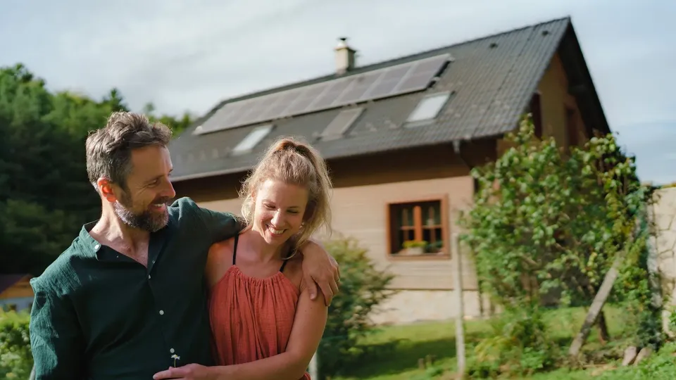 Couple embracing outdoors in front of a house with solar panel