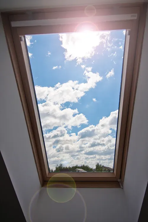 Takfönster med utsikt över blå himmel och moln.