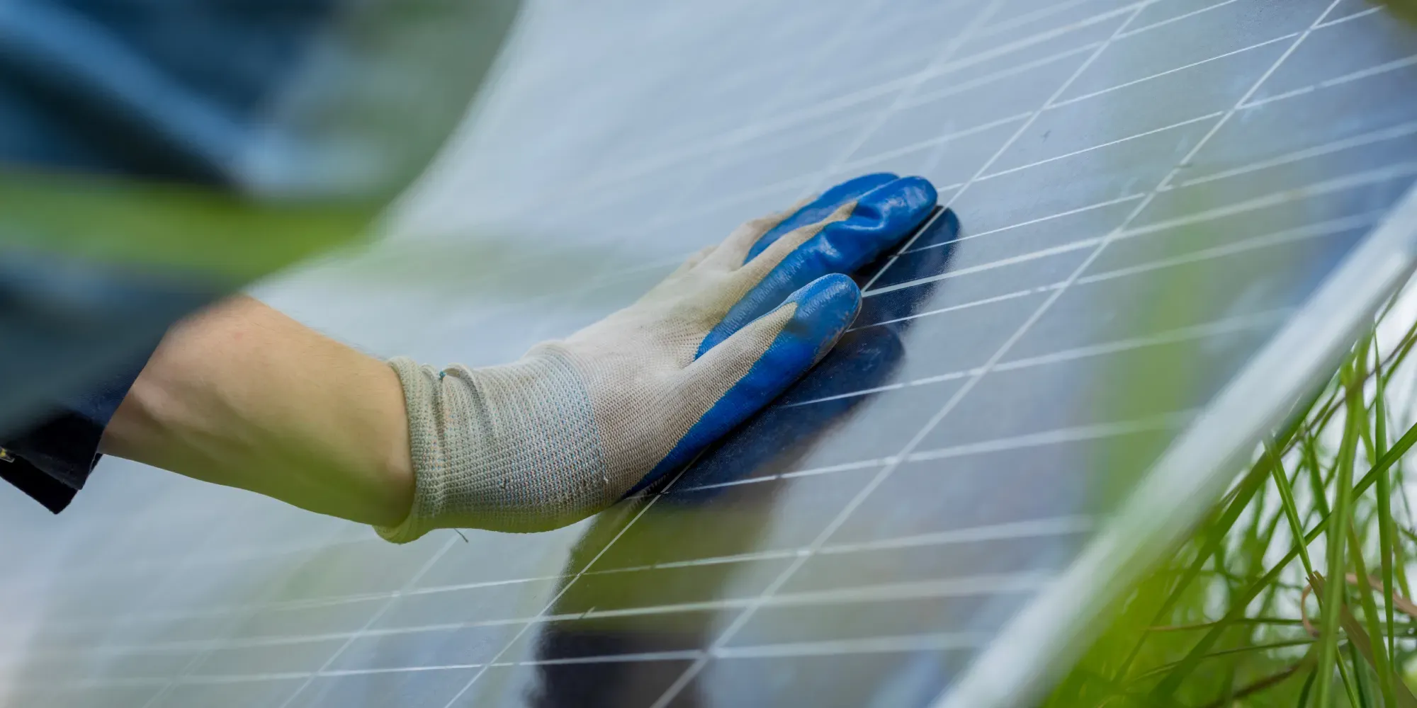 Mano enguantada de un trabajador limpiando un panel solar.