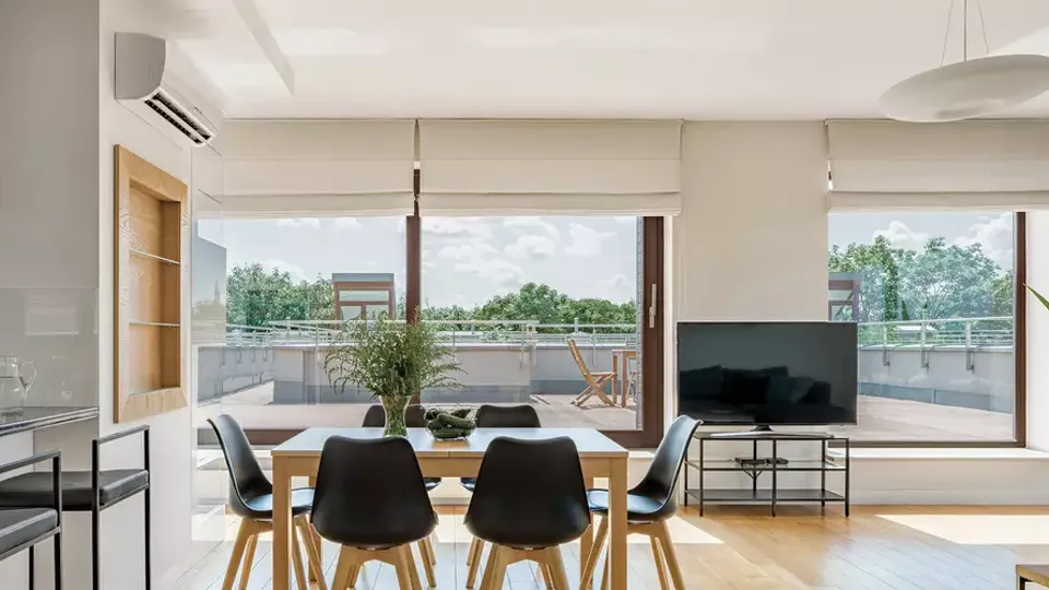 Moderne spisestue med træbord og sorte stole med udsigt til terrasse.