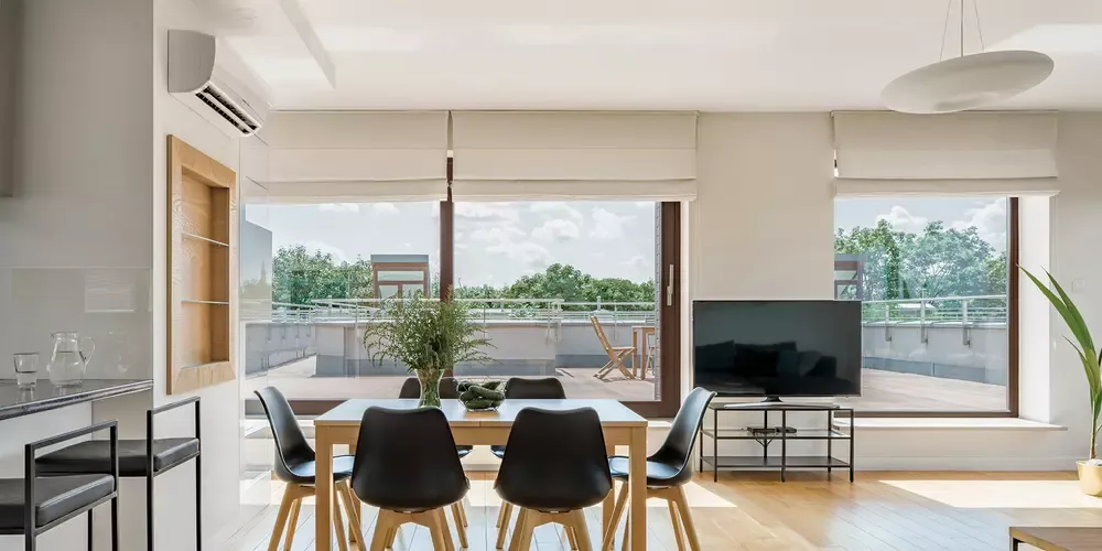 Moderne spisestue med træbord og sorte stole med udsigt til terrasse.