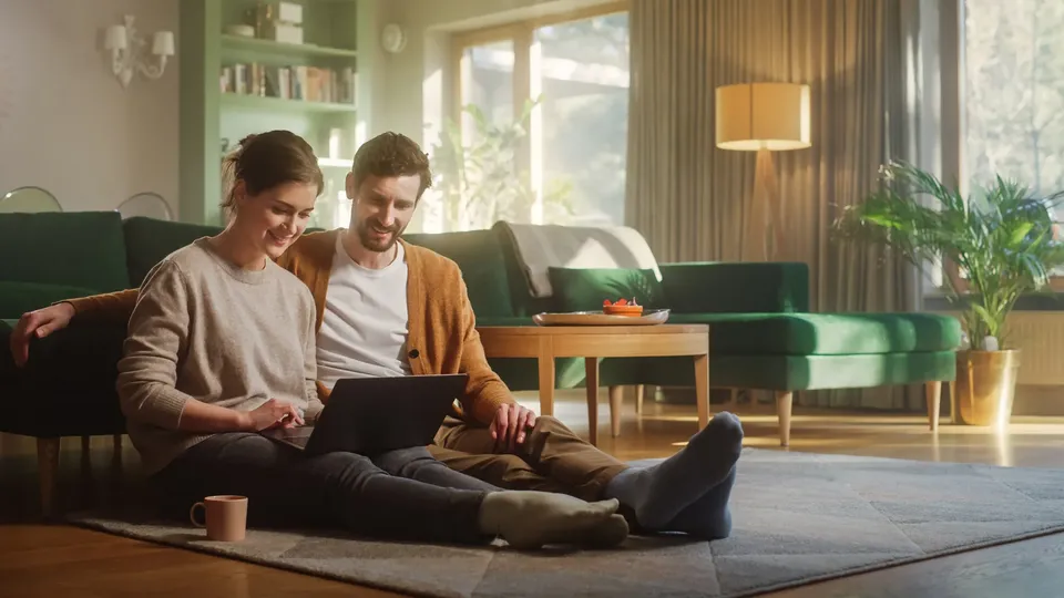 Par sidder på gulvet og ser på computer sammen.