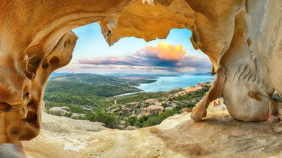 Vista del paesaggio costiero con mare turchese incorniciato da arco di roccia naturale.