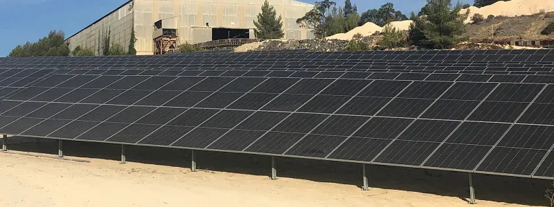 Grande matriz de painéis solares em frente a edifício industrial.