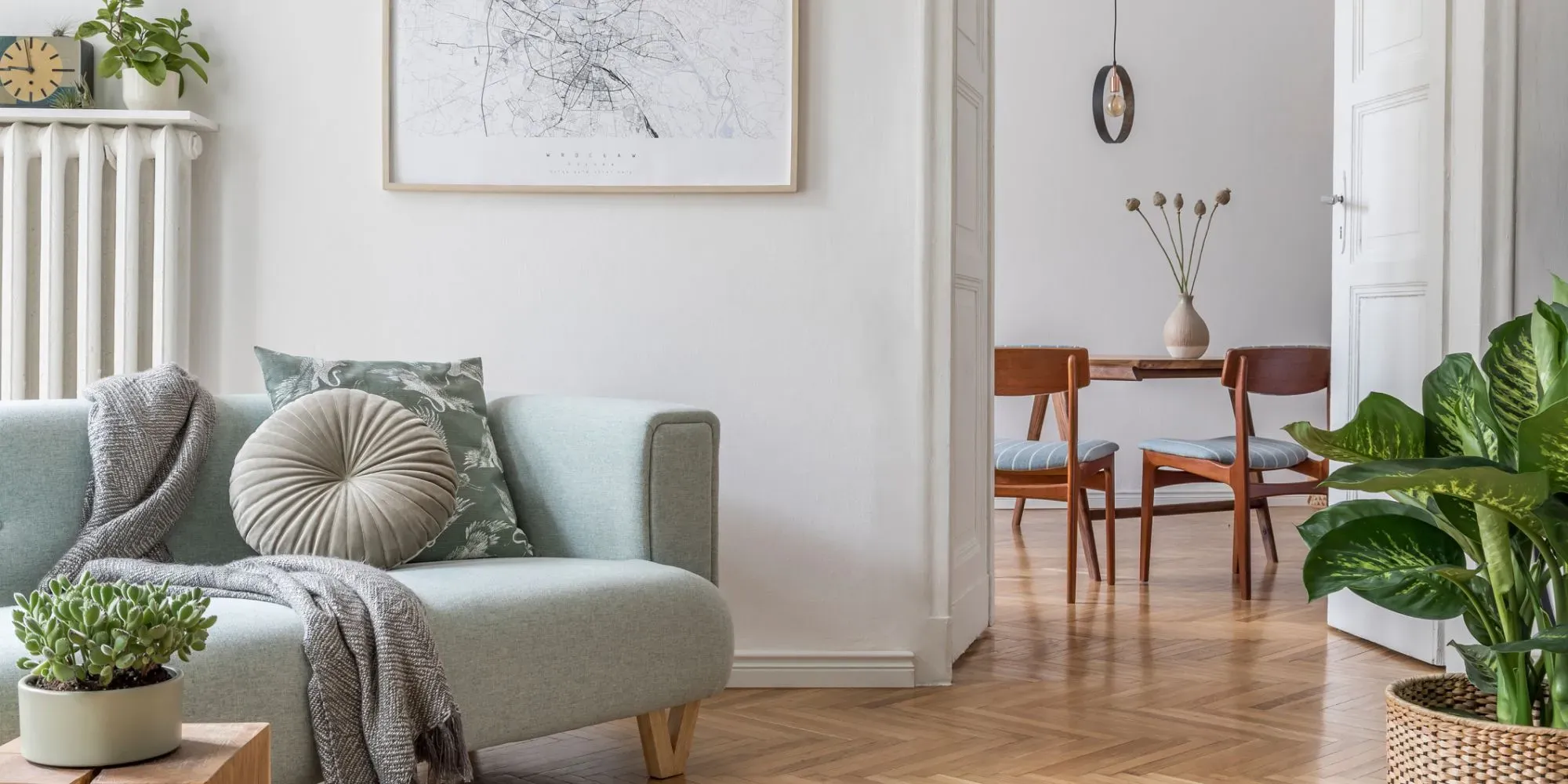 Modernt vardagsrum med ljusblå soffa, trämatsstolar och krukväxter.