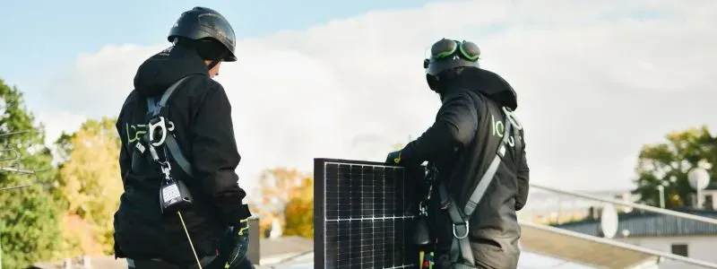 Due installatori di pannelli solari al lavoro su un tetto.
