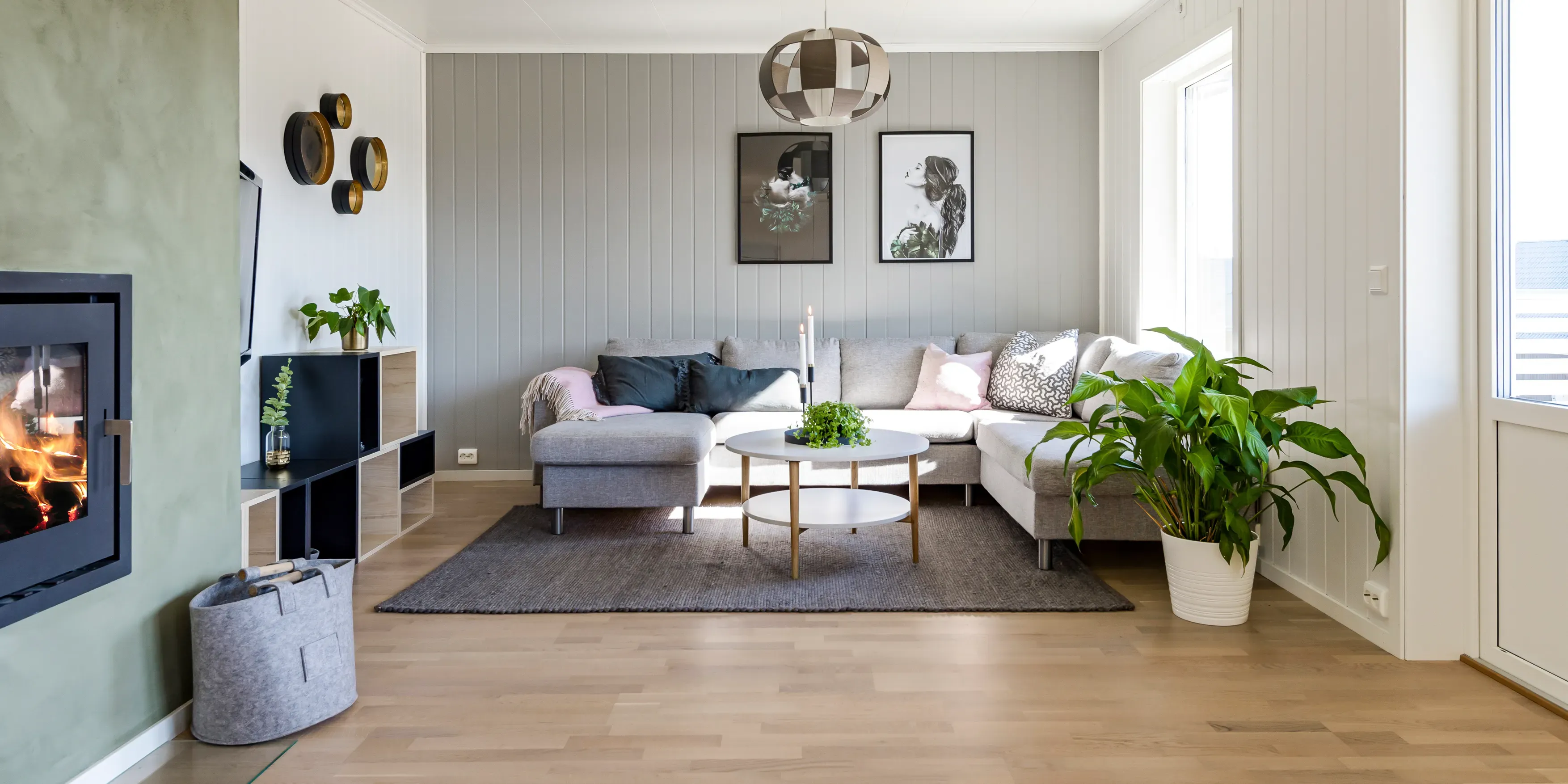 Skandinavisk stue med grå sofa, sofabord og peis.