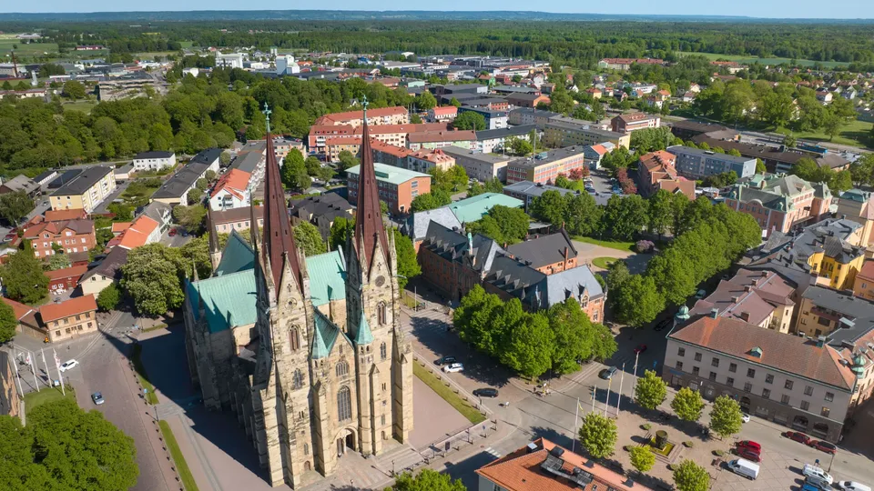 Utsikt över en stad som är omgiven av skog, med en kyrka i förgrunden.