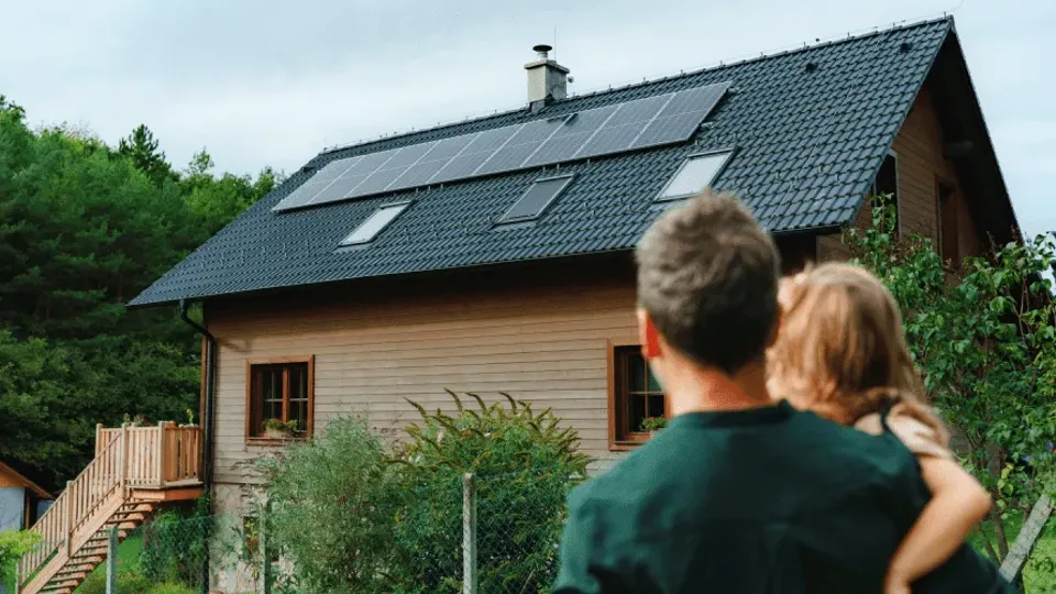 Man and child viewing house with solar panels on roof.