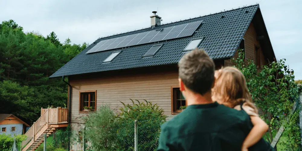 Man and child viewing house with solar panels on roof.