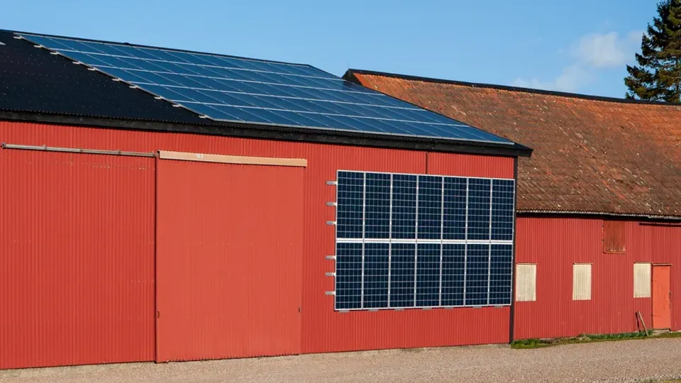 Röd ekonomibyggnad med solceller på tak och vägg.