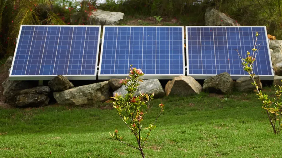 Solceller monteret på et stativ på jorden i en have