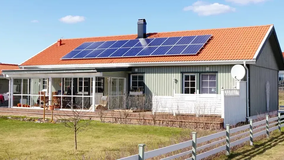 Solcellspaneler installerade på en ljusgrön villa i solsken.