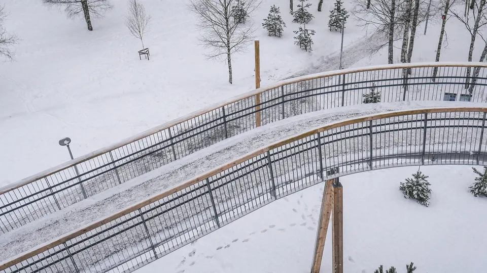 Buet snødekt fotgjengerbroer som slynger seg gjennom snøkledd skog med nakne trær.