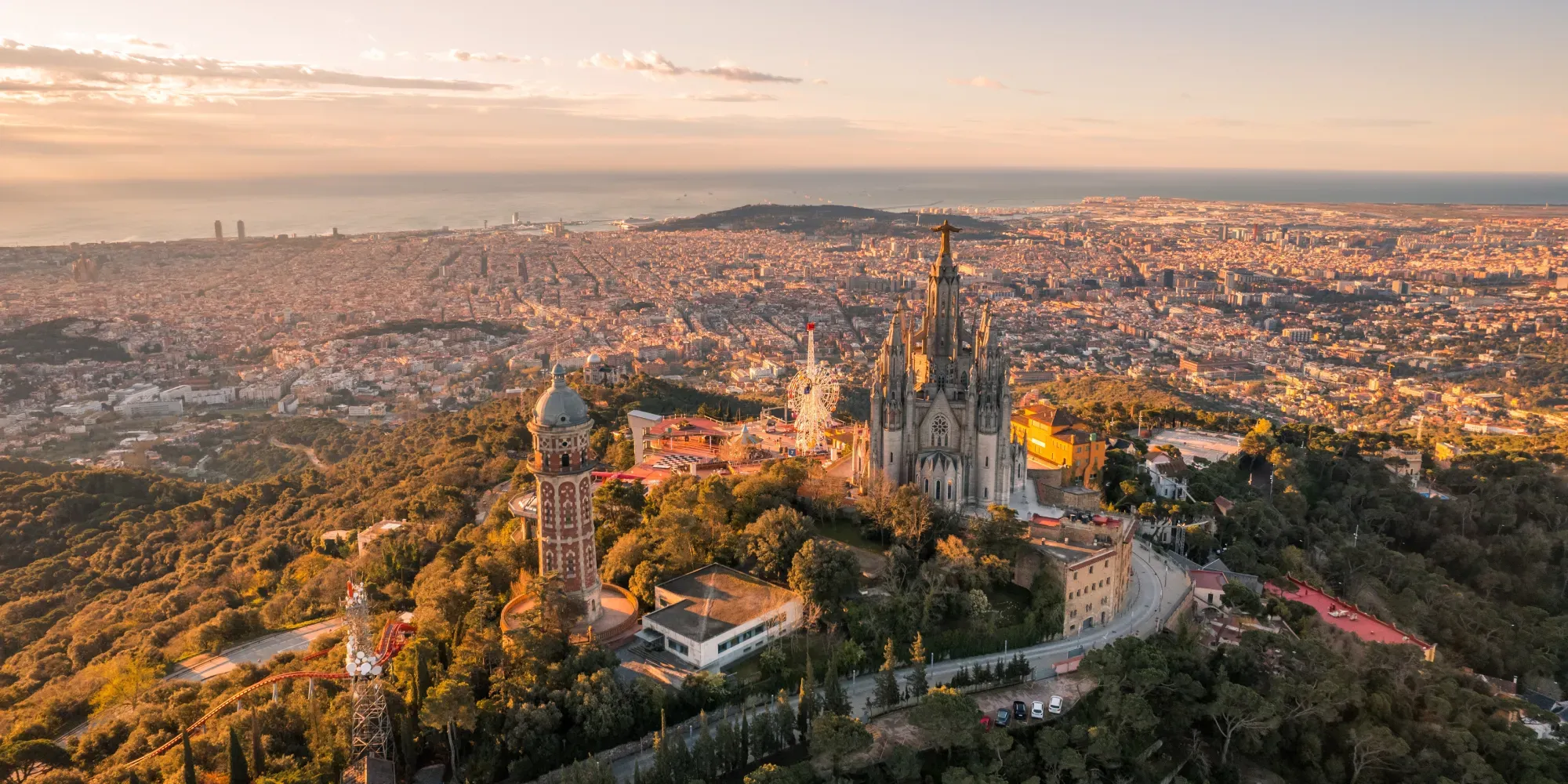 Vista aérea de Barcelona con iglesia gótica y paisaje urbano al atardecer.