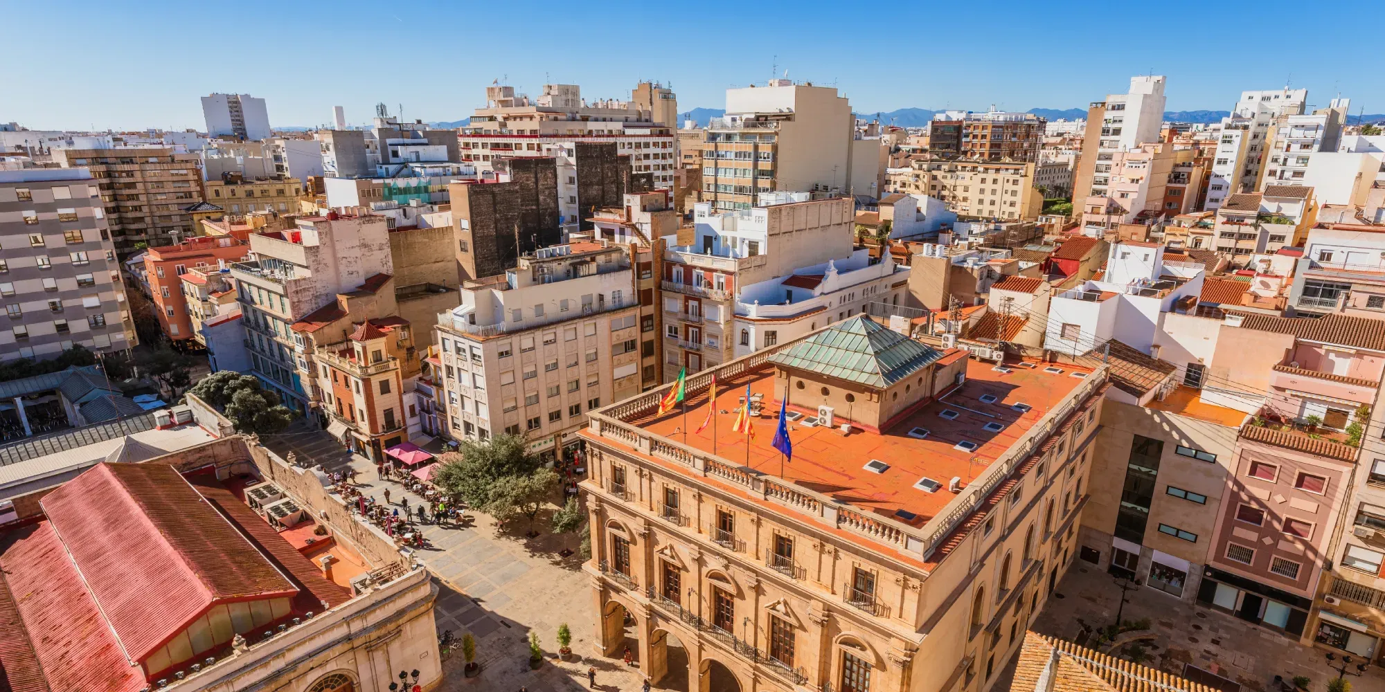 Vista aérea de paisaje urbano con edificios de tejado naranja y plaza central.