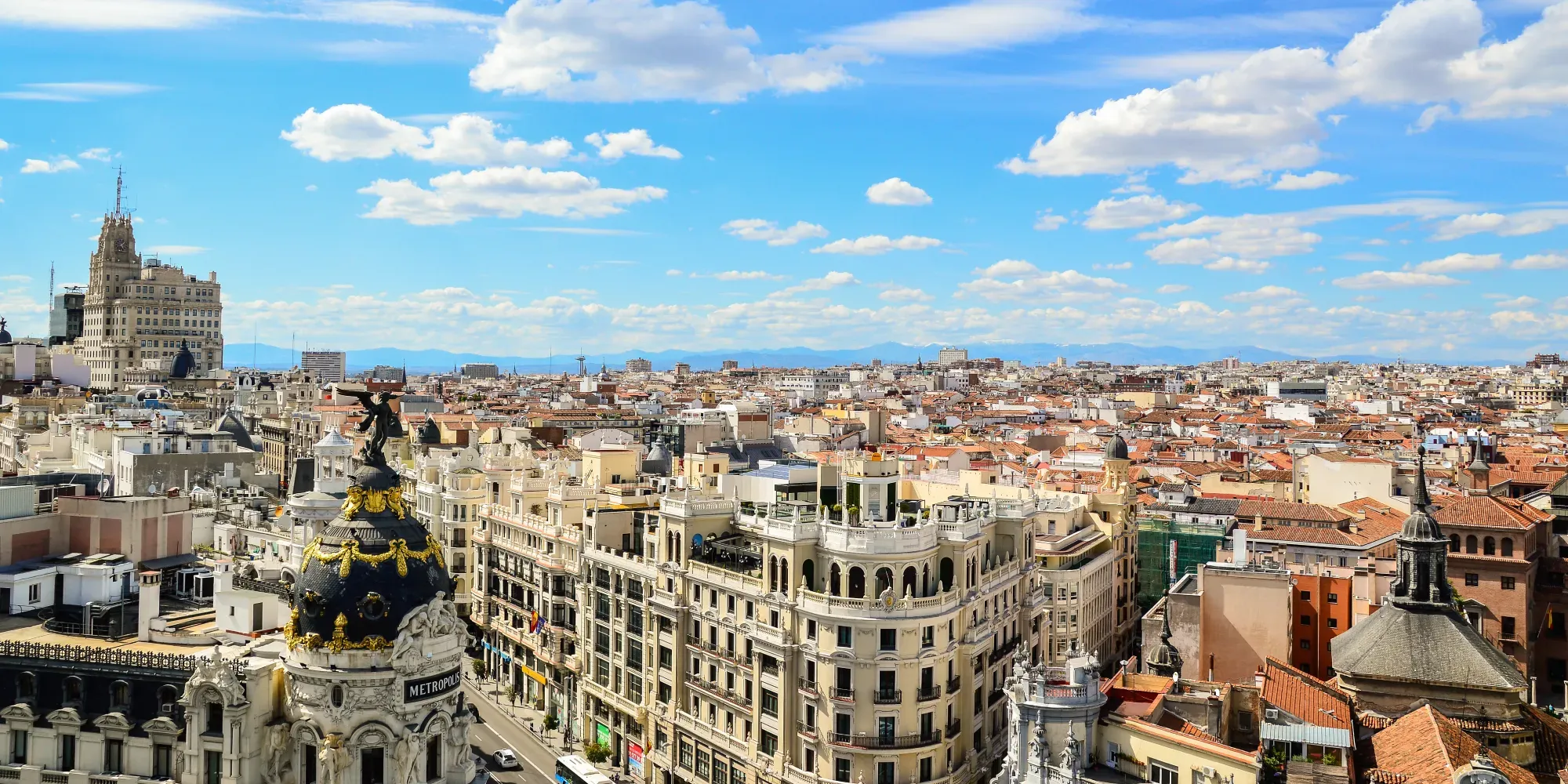 Vista aérea del paisaje urbano de Madrid con edificio ornamentado y estatua dorada en primer plano.