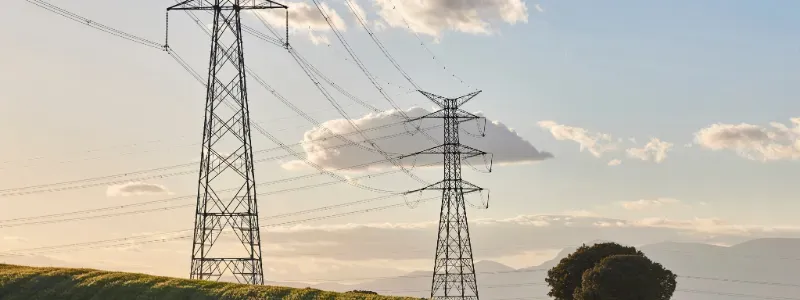 Painéis solares em campo com água e horizonte urbano ao fundo.