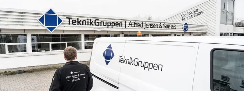 Medarbejder fra Teknikgruppen foran firmabil.