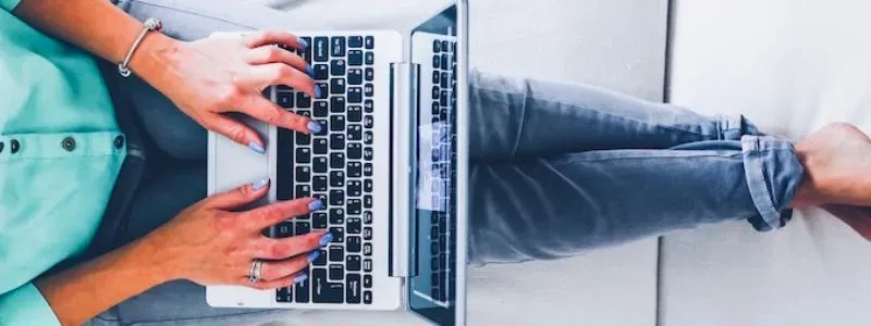 Person i en sofa med computer på skødet.