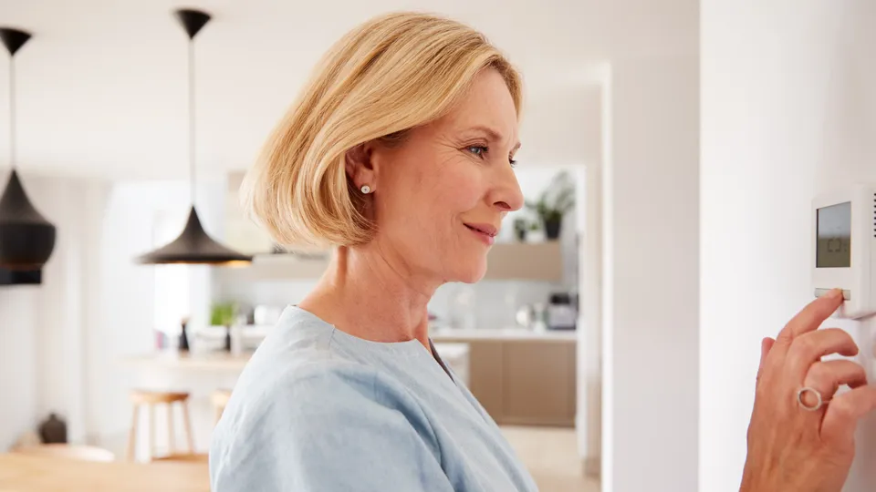 Kvinne justerer et digitalt veggtermostat.