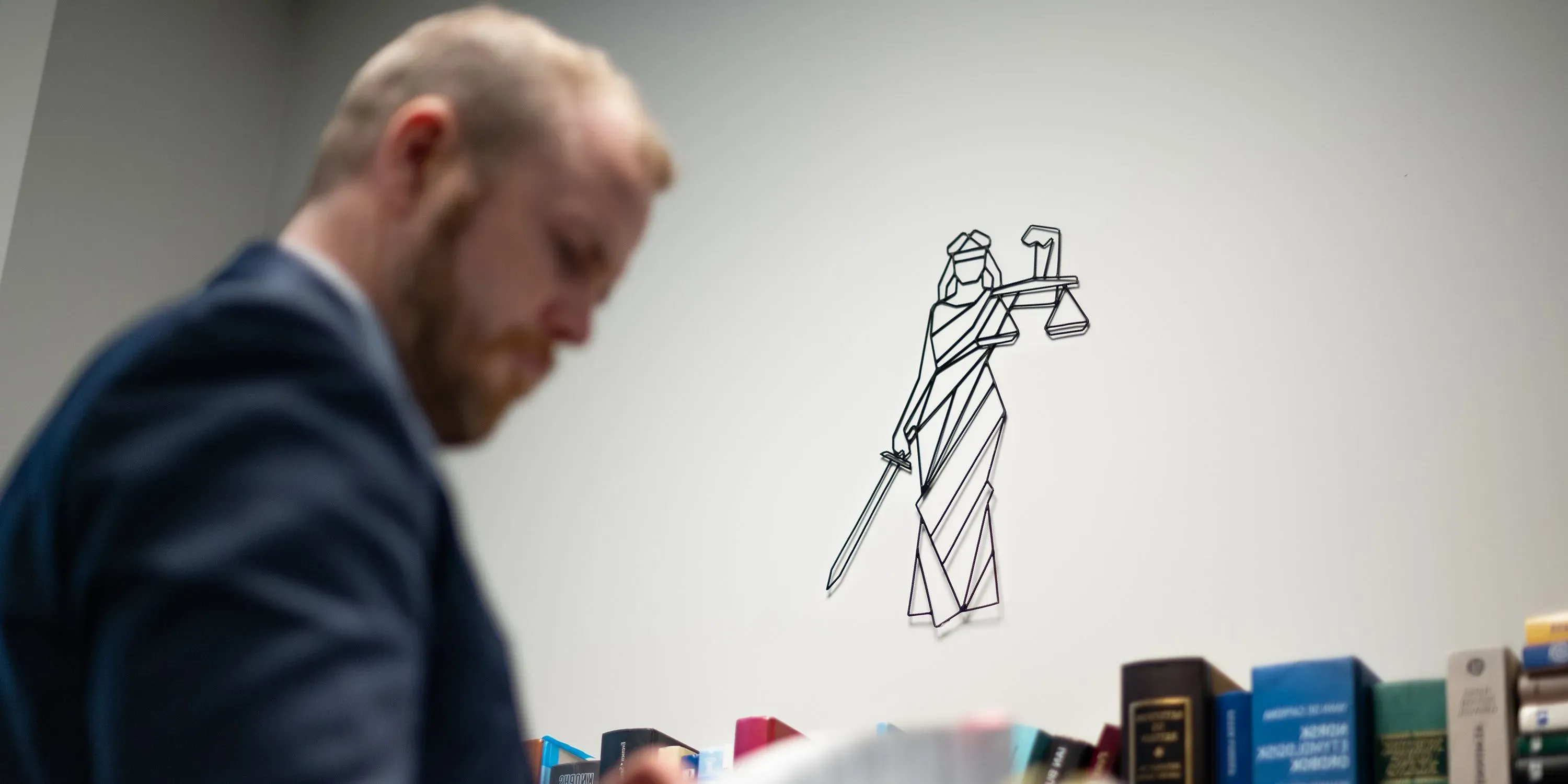 Bilde av en advokat med installasjon av rettferdighetsgudinnen Justitia i bakgrunnen.