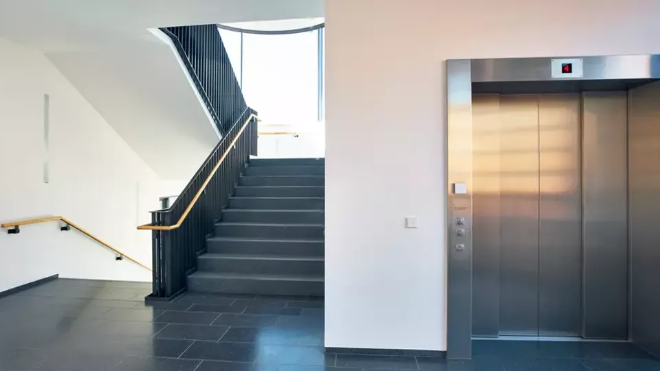 Modernt byggnadsentrérum med trappa och hiss.