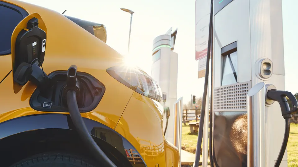 Pictured is a bright yellow EV being charged at a public charging station.