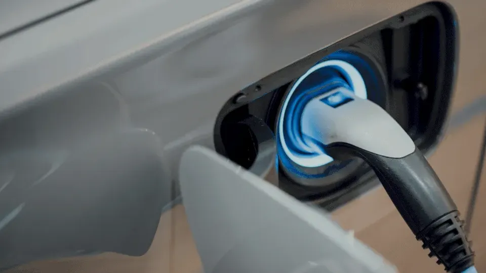 Electric vehicle charging cable plugged into car port.