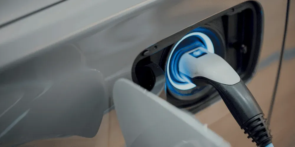 Electric vehicle charging cable plugged into car port.