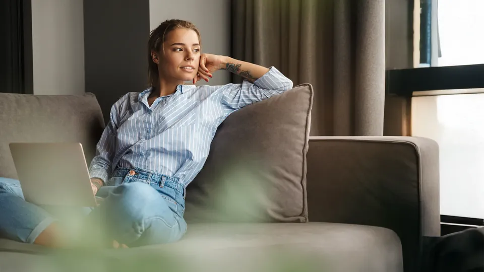 Kvinde sidder i sin sofa og kigger til sin venstre.